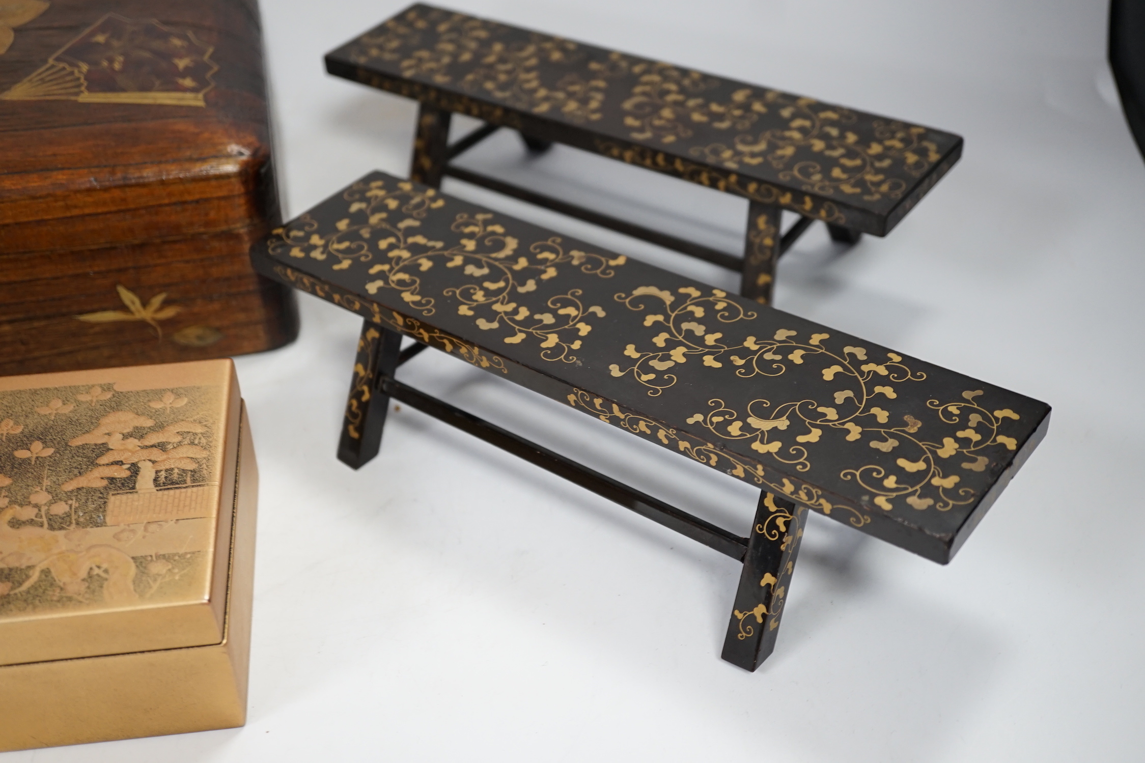 A group of Japanese lacquer wares, comprising pair of miniature benches and two boxes, Meiji period and later, largest 25cm wide